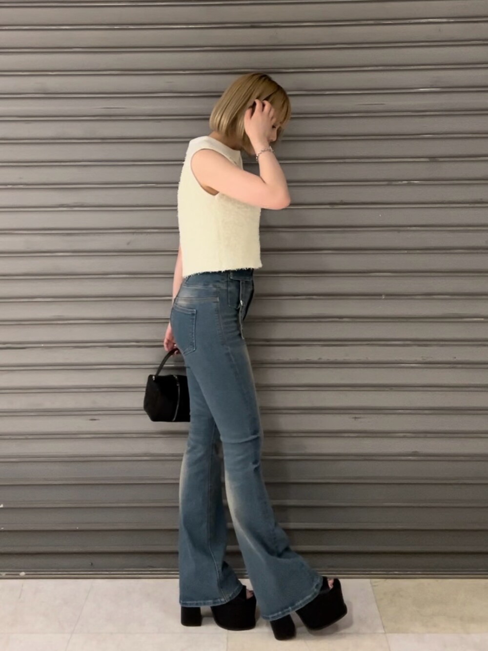 ホワイト系のタンクトップ、ブルー系のデニムパンツ、ブラック系のハンドバッグを着用したレディースの夏コーディネートの2枚目の写真