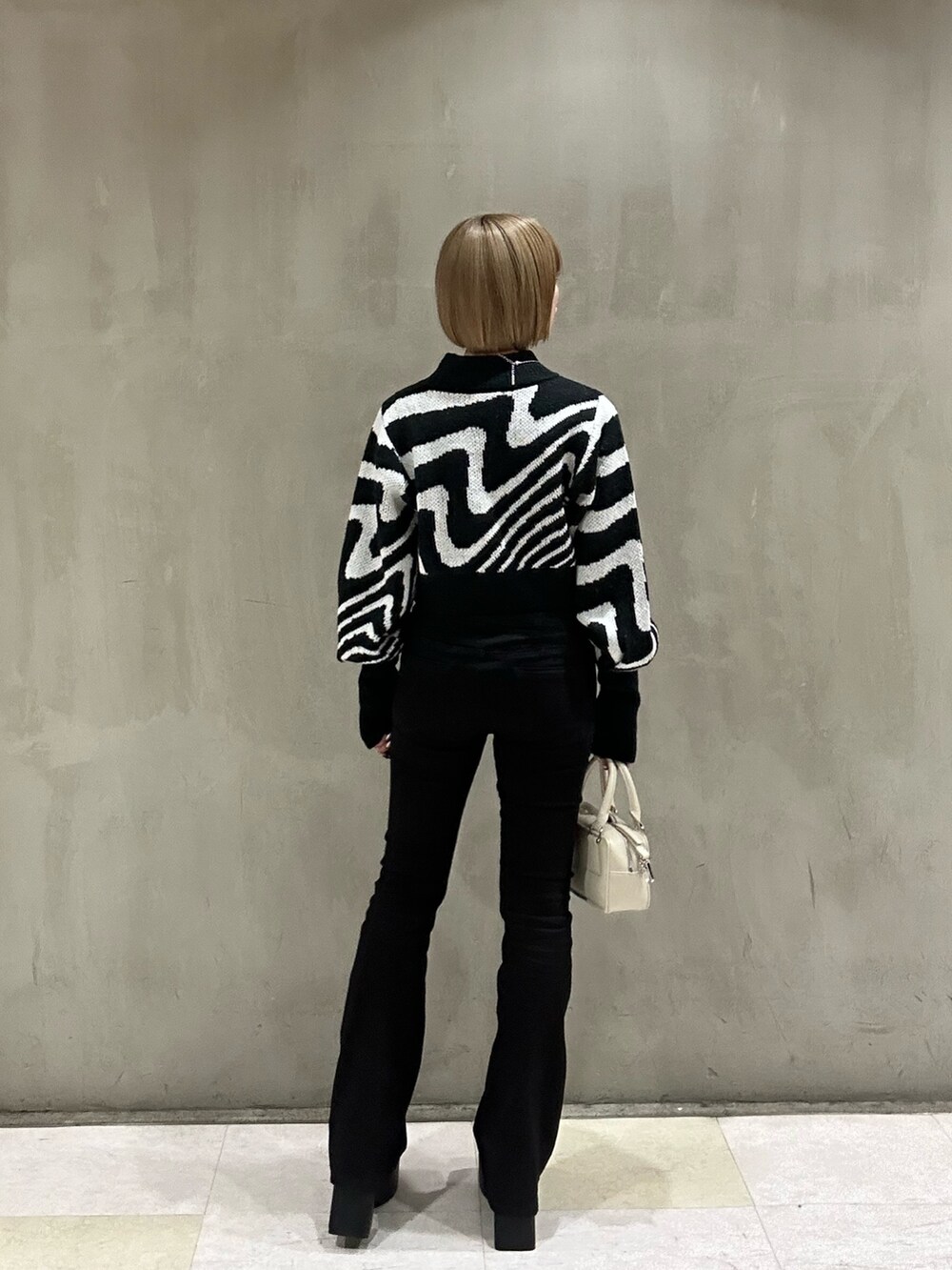 ホワイト系のダウンジャケット/コート、ブラック系のニット/セーター、ブラック系のデニムパンツを着用したレディースの冬コーディネートの5枚目の写真