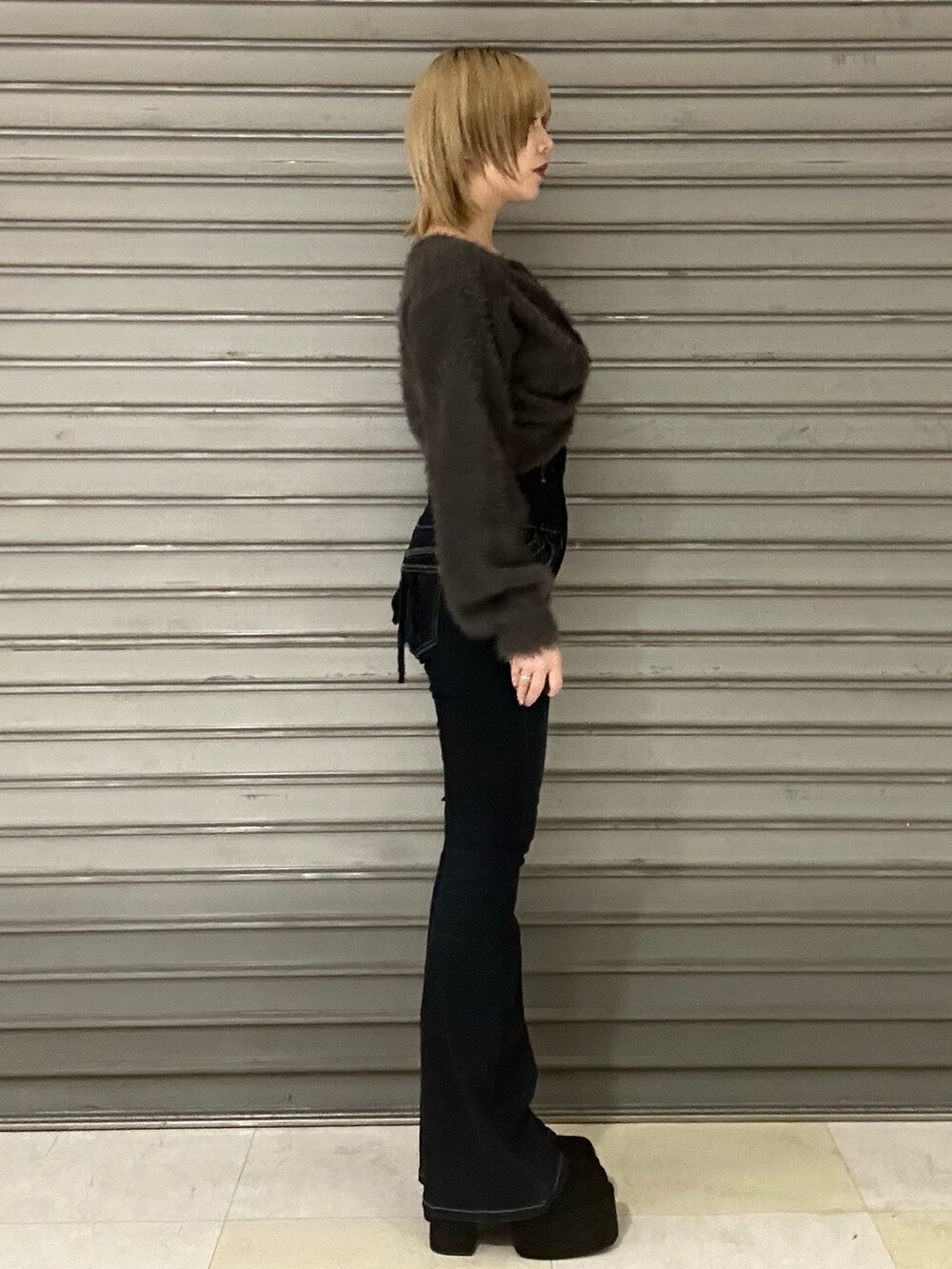 グレー系のニット/セーター、グレー系のTシャツ/カットソー、ブルー系のデニムパンツを着用したレディースの秋コーディネートの2枚目の写真