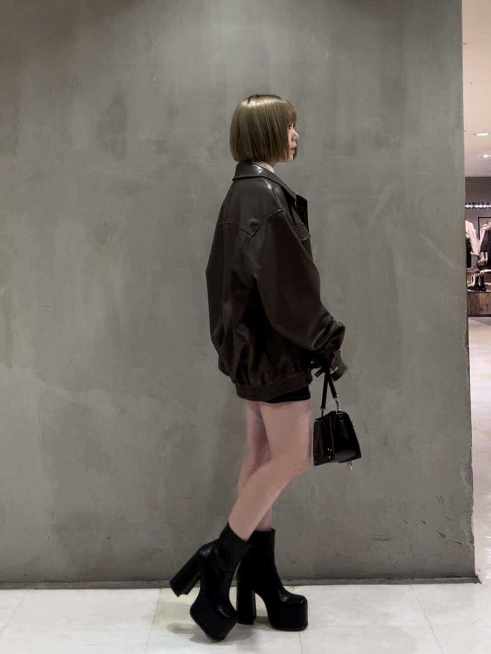 ホワイト系のニット/セーター、ブラウン系のブルゾン、ブラック系のスカートを着用したレディースの冬コーディネートの3枚目の写真