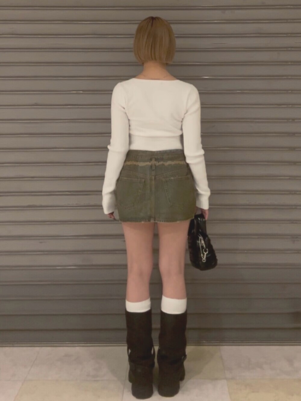 ブラウン系のブルゾン、ホワイト系のニット/セーター、ブラウン系のスカートを着用したレディースの冬コーディネートの6枚目の写真