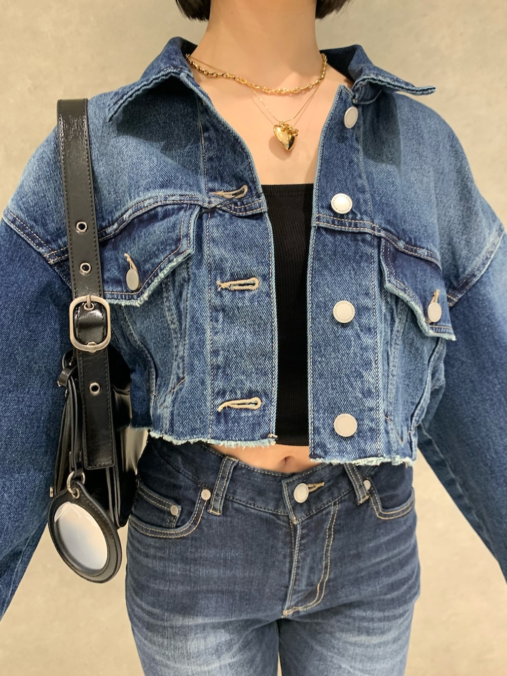 ブルー系のデニムパンツ、ブルー系のデニムジャケット、ブラック系のキャミソールを着用したレディースの春コーディネートの3枚目の写真