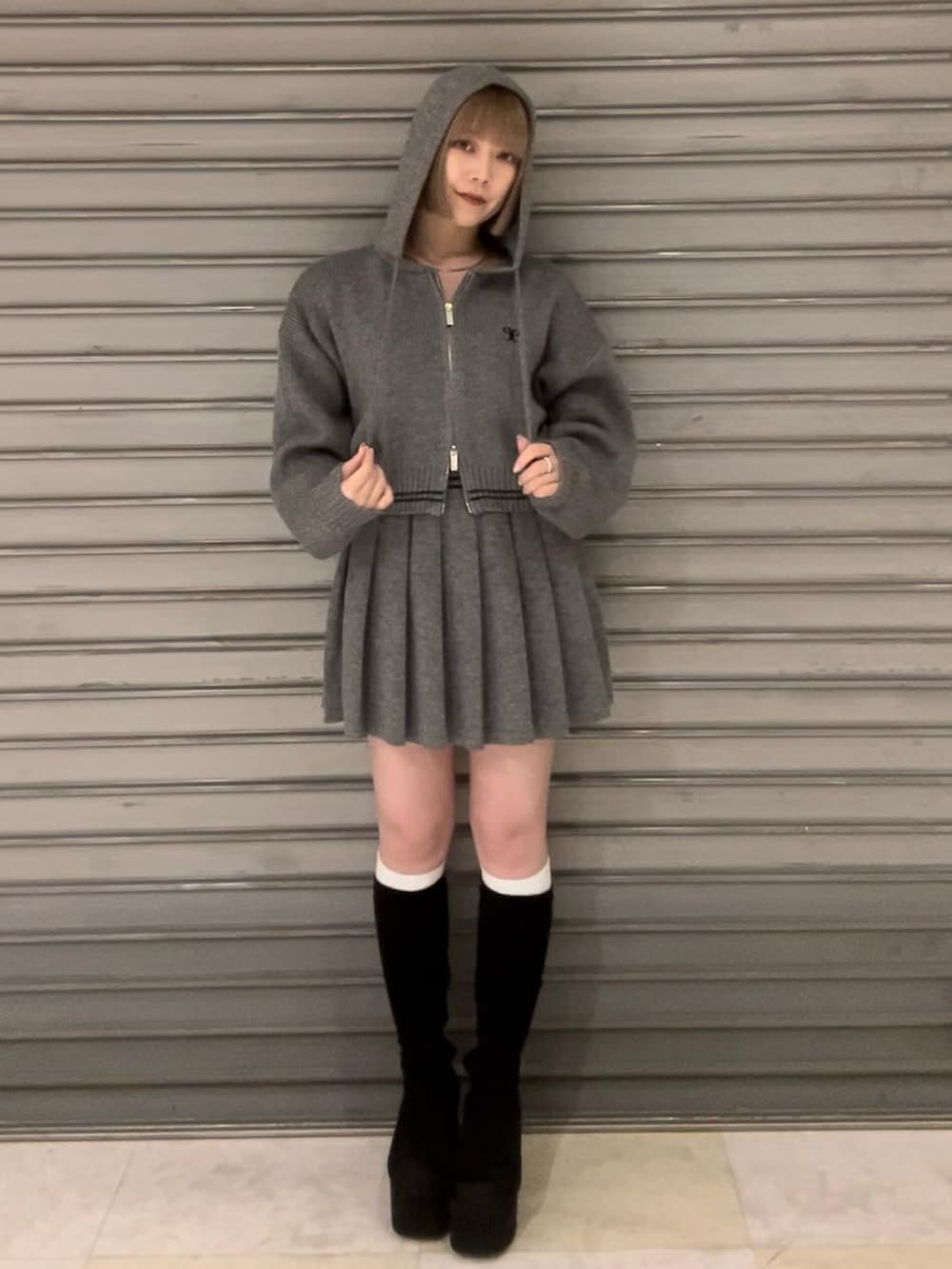 グレー系のニット/セーター、グレー系のスカート、その他のブーツを着用したレディースの秋コーディネートの2枚目の写真