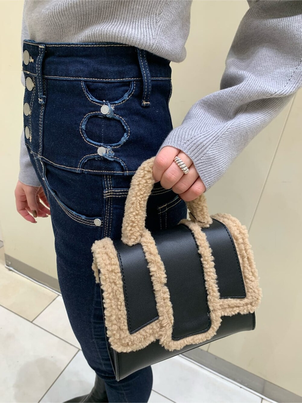 ブラック系のハンドバッグ、ブルー系のデニムパンツ、グレー系のニット/セーターを着用したレディースの秋コーディネートの5枚目の写真