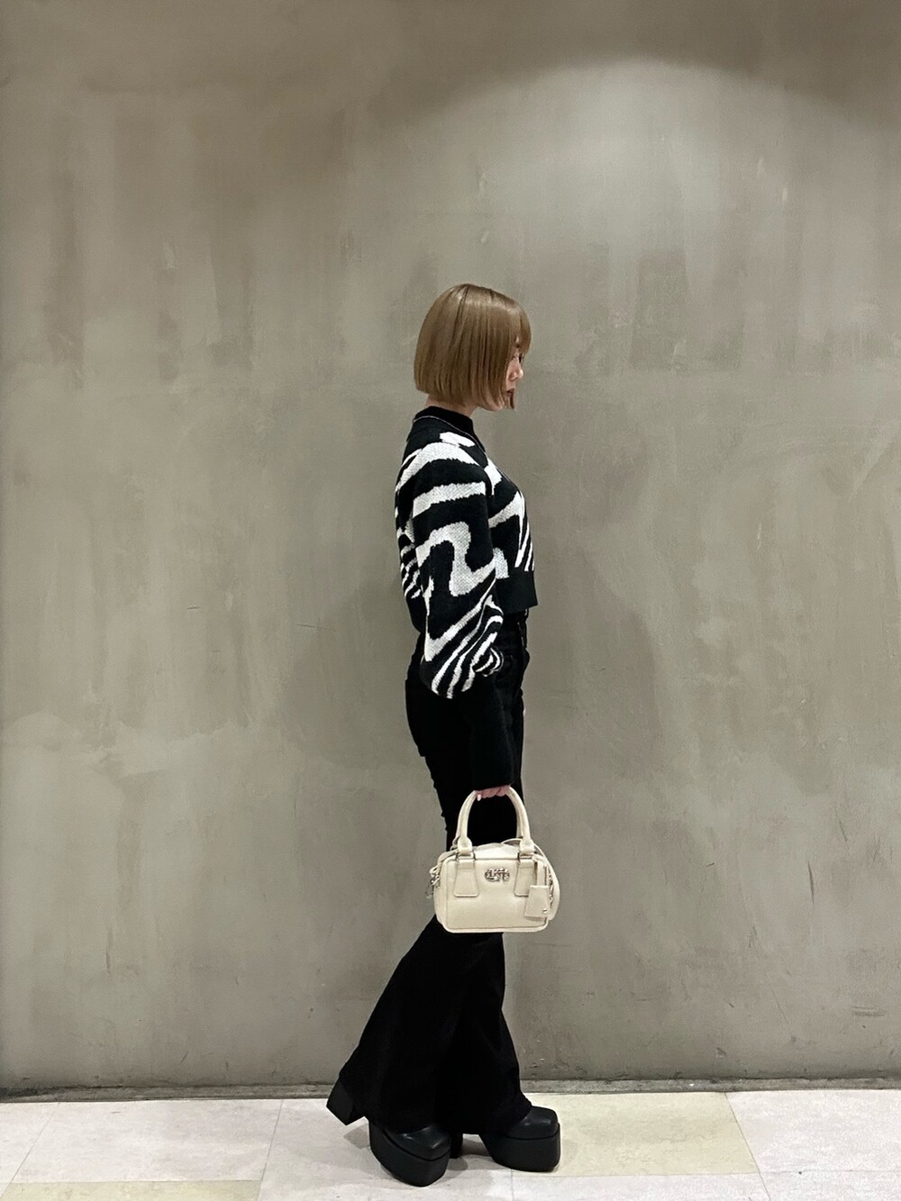 ホワイト系のダウンジャケット/コート、ブラック系のニット/セーター、ブラック系のデニムパンツを着用したレディースの冬コーディネートの4枚目の写真