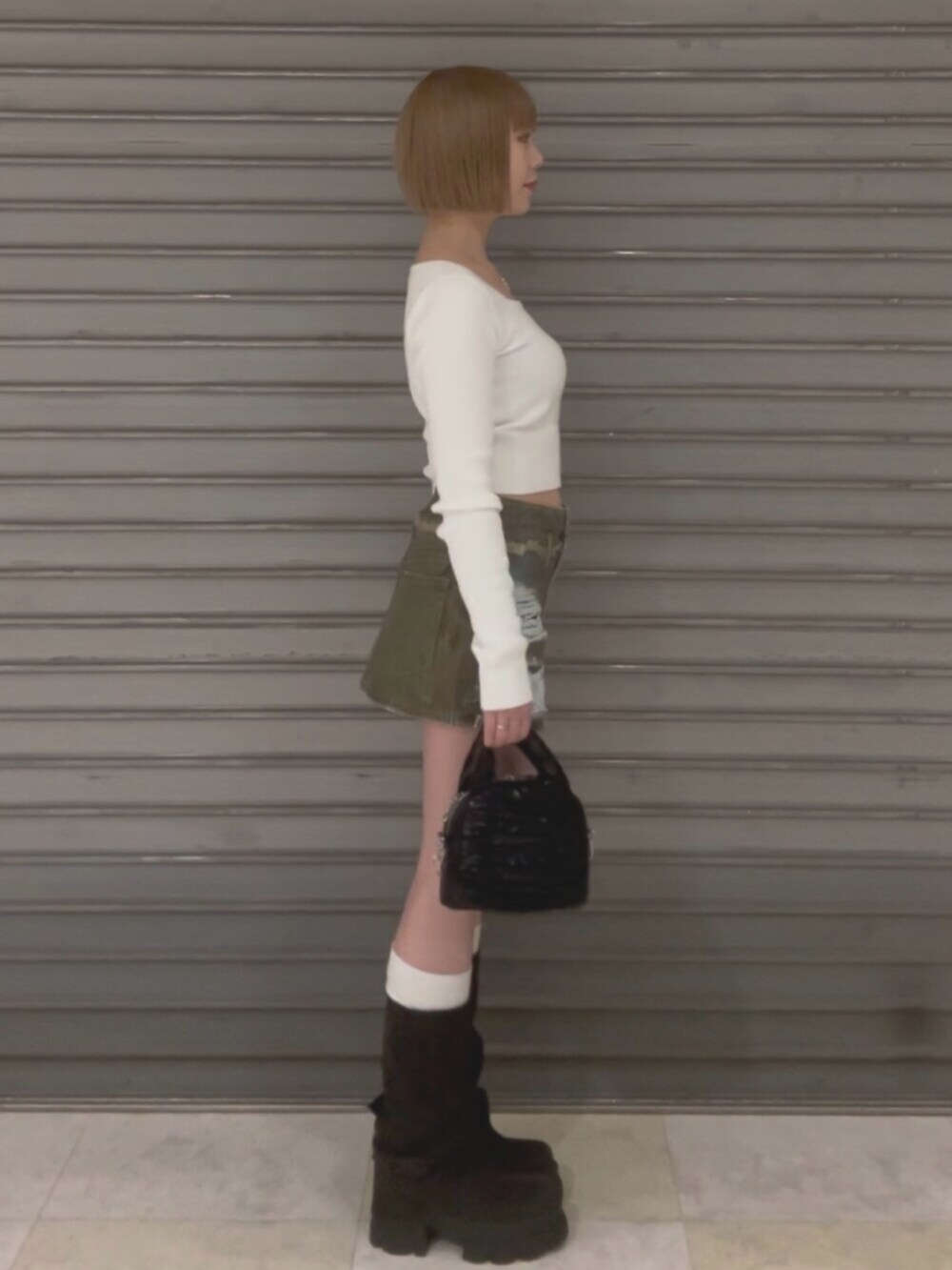 ブラウン系のブルゾン、ホワイト系のニット/セーター、ブラウン系のスカートを着用したレディースの冬コーディネートの4枚目の写真