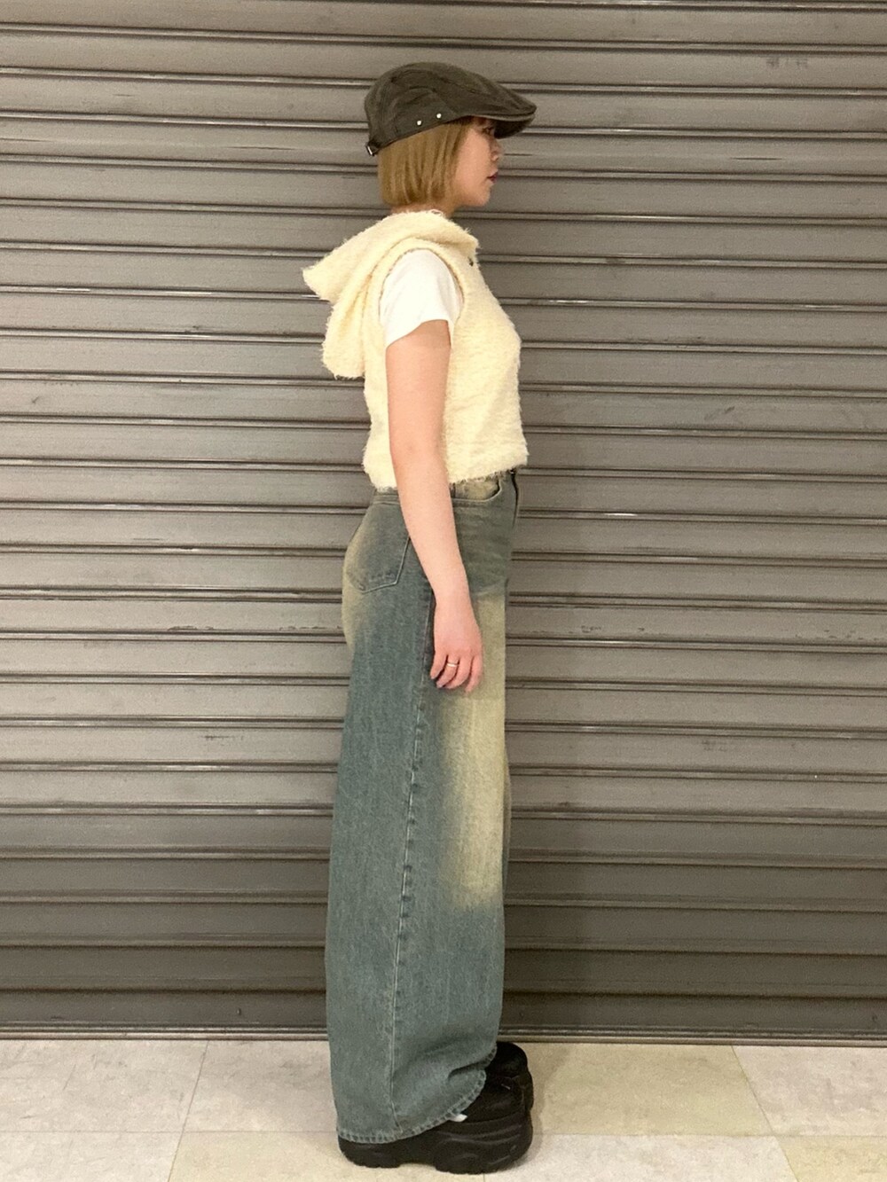 ホワイト系のニット/セーター、ホワイト系のTシャツ/カットソー、ブルー系のデニムパンツを着用したレディースの春コーディネートの2枚目の写真