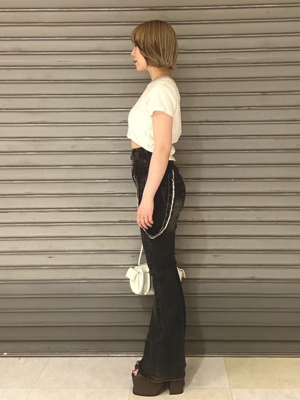 ホワイト系のTシャツ/カットソー、ブルー系のデニムパンツ、ホワイト系のハンドバッグを着用したレディースの夏コーディネートの2枚目の写真