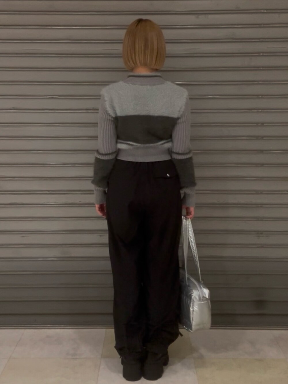 グレー系のニット/セーター、ブラック系のその他パンツ、シルバー系のボストンバッグを着用したレディースの冬コーディネートの3枚目の写真