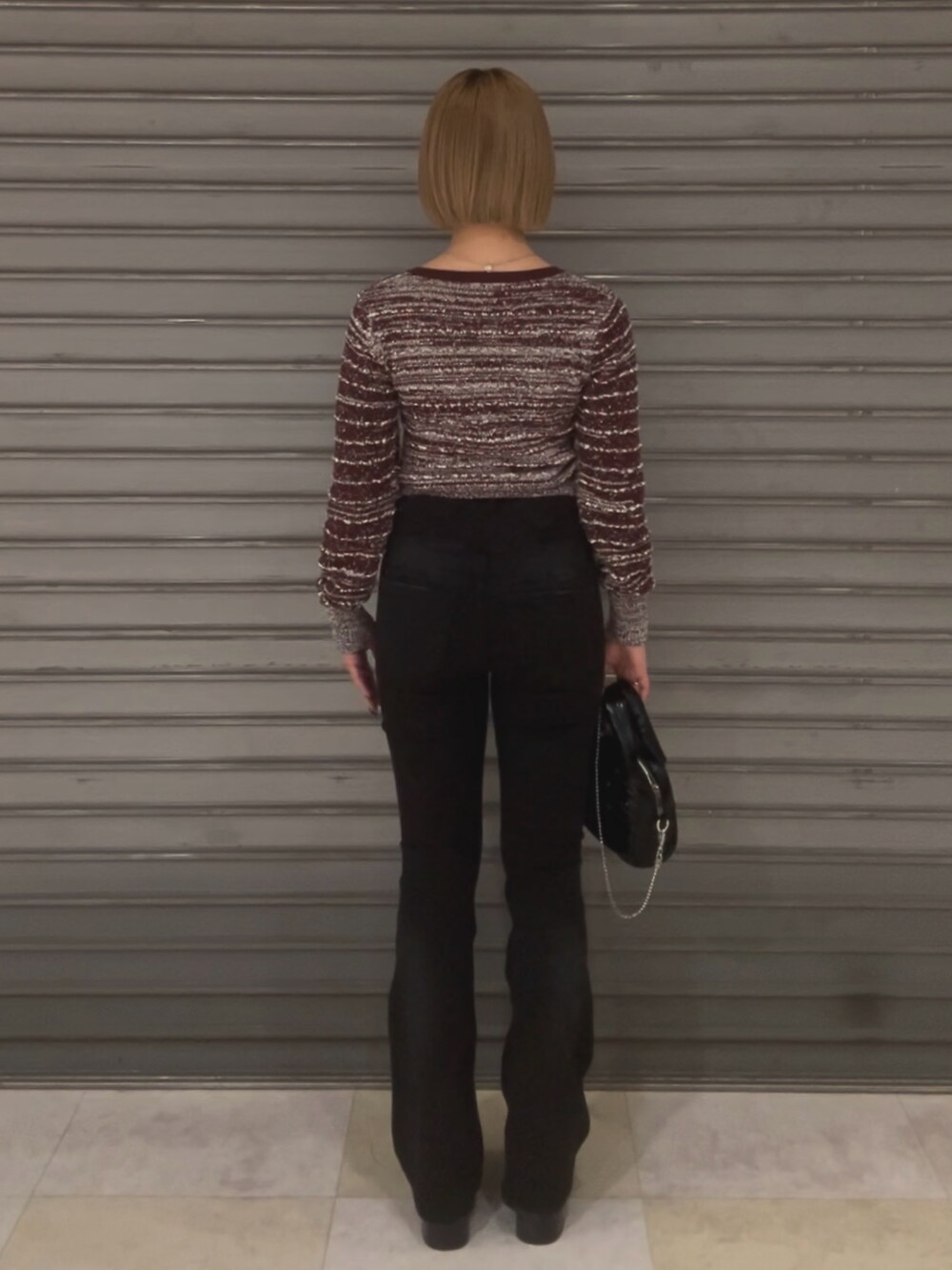 ブラック系のハンドバッグ、レッド系のニット/セーター、ブラック系のデニムパンツを着用したレディースの冬コーディネートの3枚目の写真