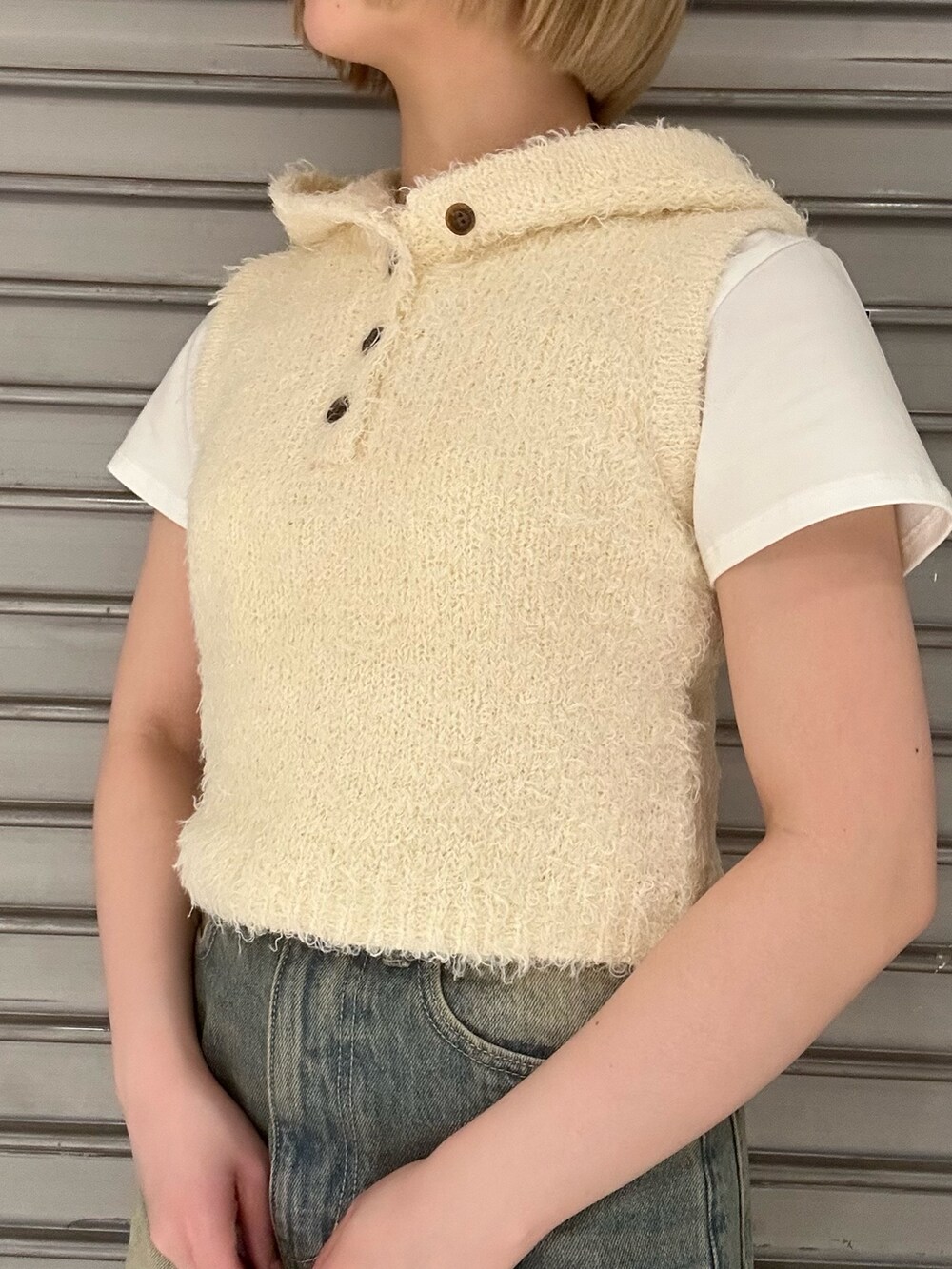 ホワイト系のニット/セーター、ホワイト系のTシャツ/カットソー、ブルー系のデニムパンツを着用したレディースの春コーディネートの5枚目の写真