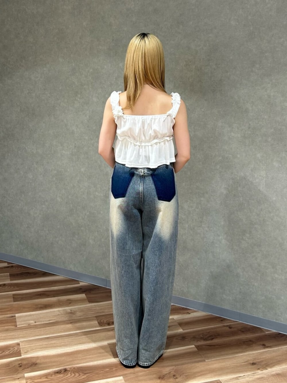 ホワイト系のタンクトップ、ブルー系のデニムパンツ、ブラック系のサンダルを着用したレディースの夏コーディネートの3枚目の写真