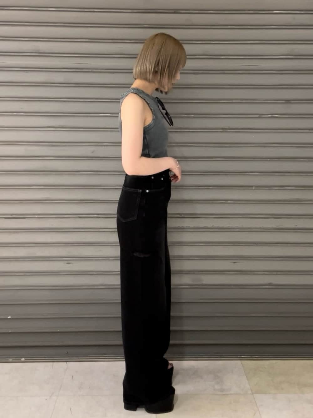 ブルー系のタンクトップ、ブラック系のデニムパンツ、ブラック系のハンドバッグを着用したレディースの夏コーディネートの2枚目の写真
