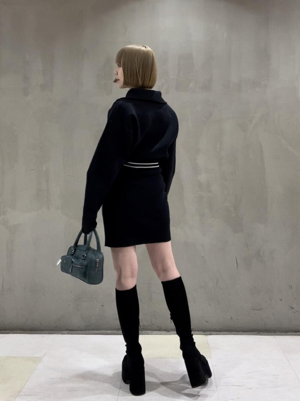 ホワイト系のダウンベスト、ブルー系のニット/セーター、ブルー系のスカートを着用したレディースの秋コーディネートの6枚目の写真