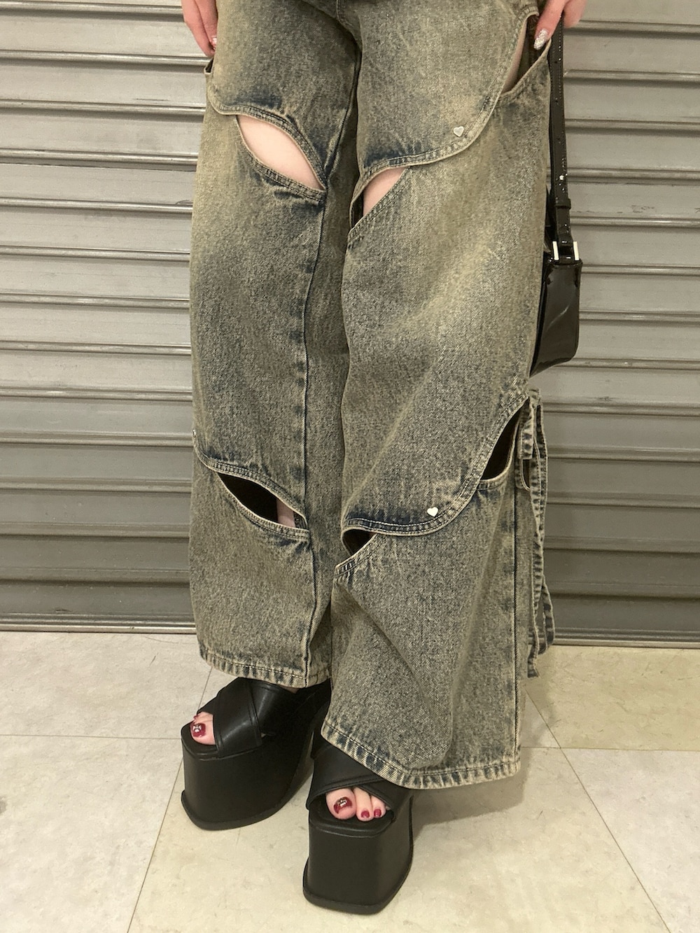 ブラック系のショルダーバッグ、ホワイト系のTシャツ/カットソー、ブルー系のデニムパンツを着用したレディースの春コーディネートの5枚目の写真