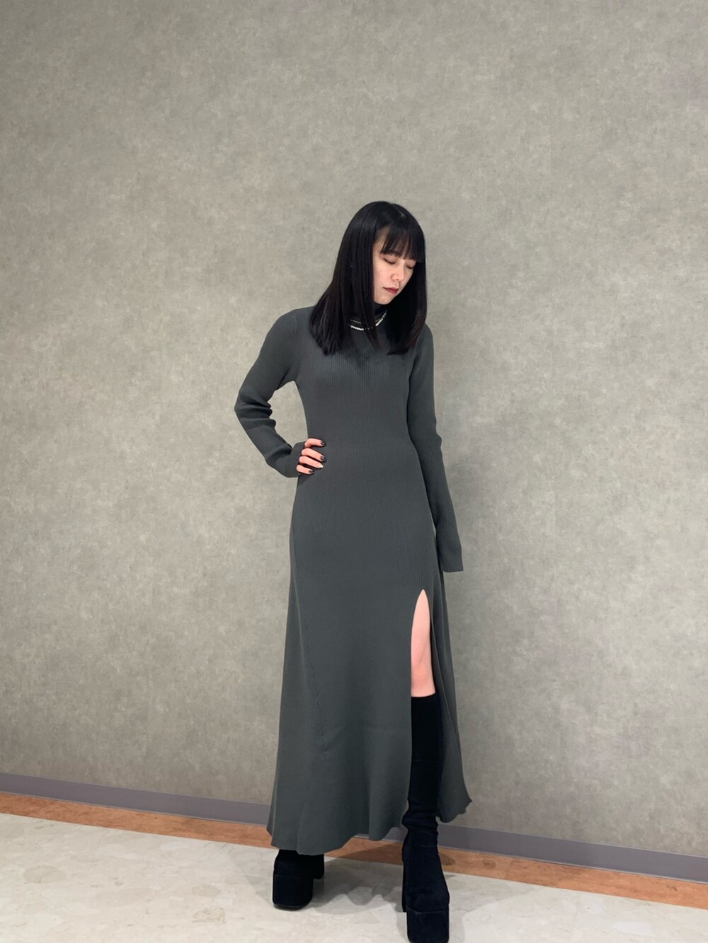 グレー系のワンピース、ブラック系のダウンジャケット/コート、ブラック系のブーツを着用したレディースの冬コーディネートの7枚目の写真