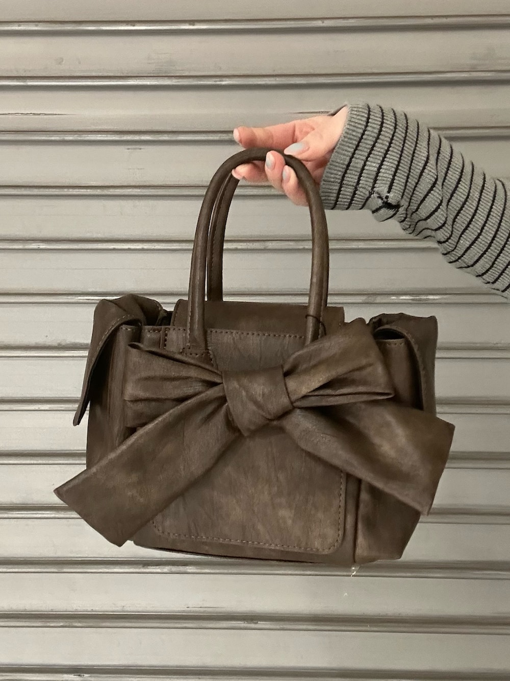 ブラック系のブーツ、グレー系のニット/セーター、ブラック系のデニムパンツを着用したレディースの冬コーディネートの6枚目の写真