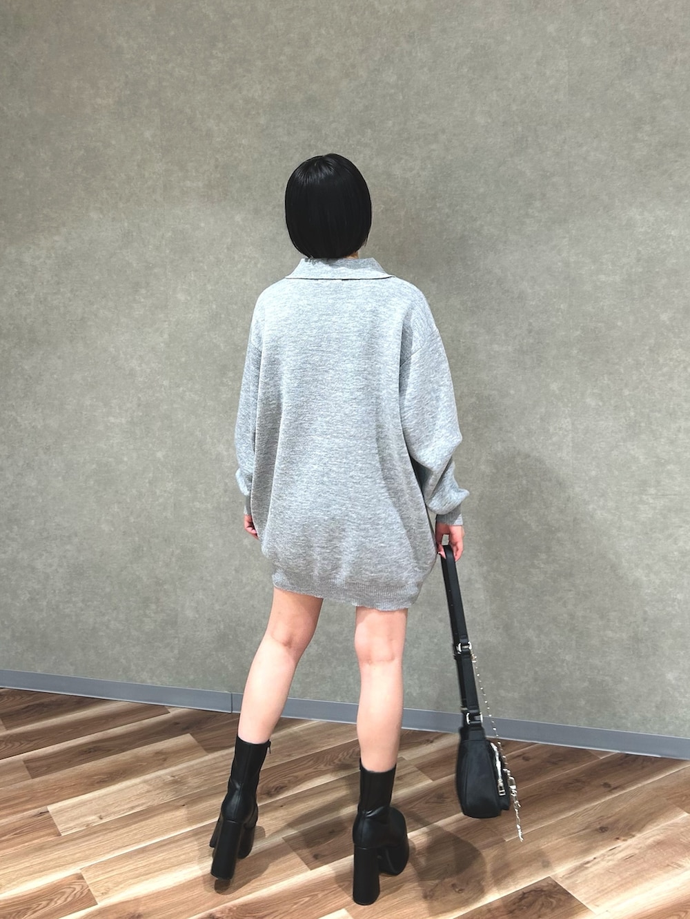 グレー系のワンピース、ホワイト系のハンドバッグ、ブラック系のブーツを着用したレディースの秋コーディネートの3枚目の写真
