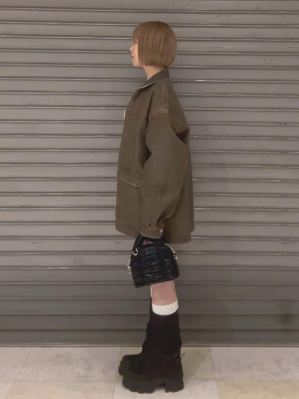 ブラウン系のブルゾン、ホワイト系のニット/セーター、ブラウン系のスカートを着用したレディースの冬コーディネートの3枚目の写真