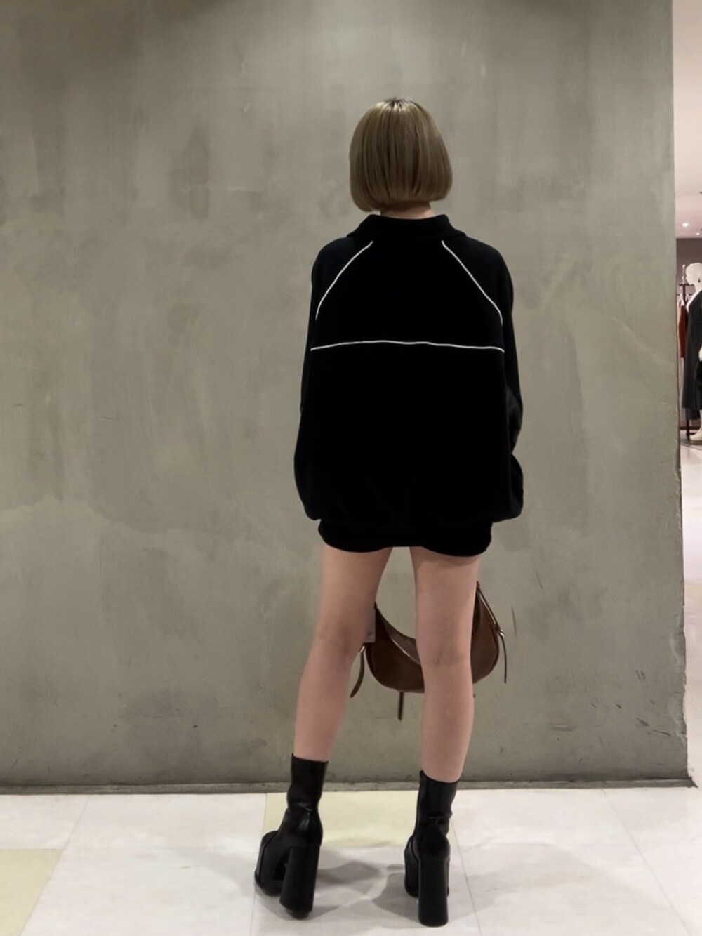 ブラック系のTシャツ/カットソー、ブラック系のスカート、ブラウン系のハンドバッグを着用したレディースの冬コーディネートの5枚目の写真