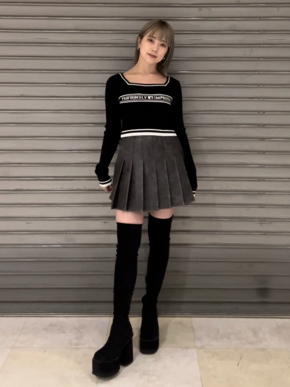 グレー系のブルゾン、グレー系のスカート、ブラック系のニット/セーターを着用したレディースの秋コーディネートの2枚目の写真