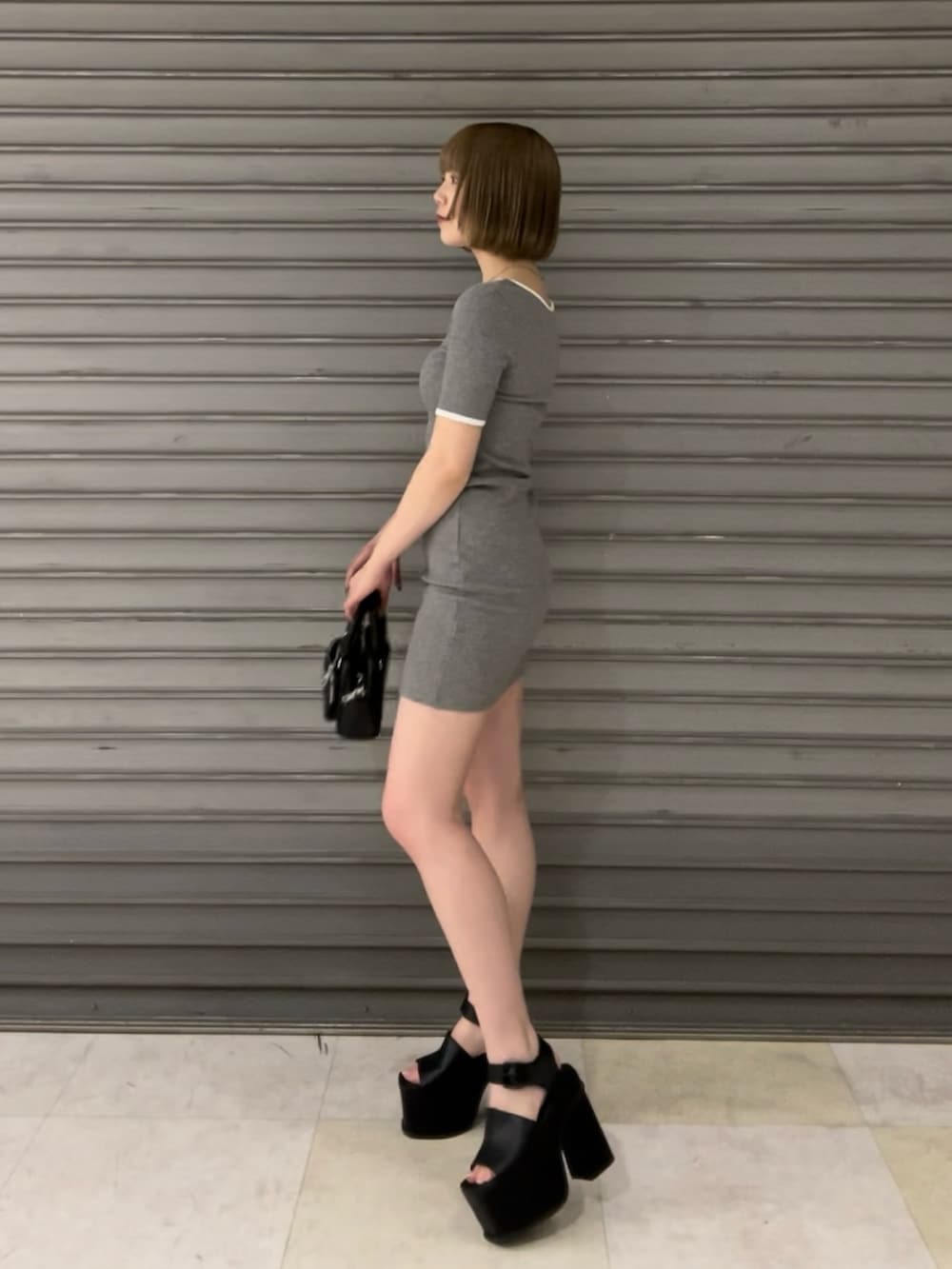 グレー系のワンピース、ブラック系のハンドバッグ、ブラック系のサンダルを着用したレディースの春コーディネートの2枚目の写真