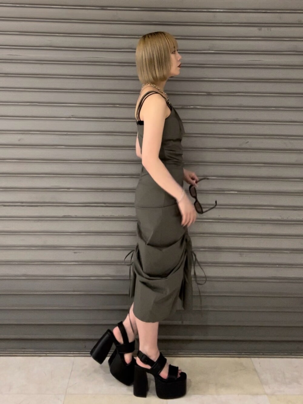 グリーン系のワンピース、ブラック系のサンダル、シルバー系のネックレスを着用したレディースの春コーディネートの2枚目の写真