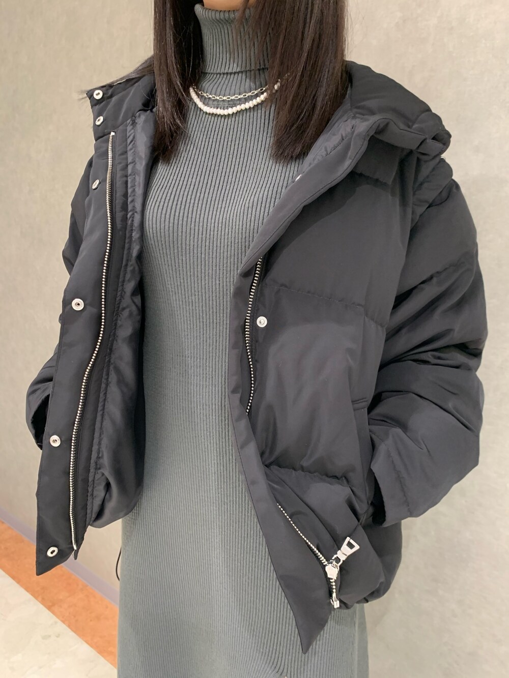 グレー系のワンピース、ブラック系のダウンジャケット/コート、ブラック系のブーツを着用したレディースの冬コーディネートの2枚目の写真