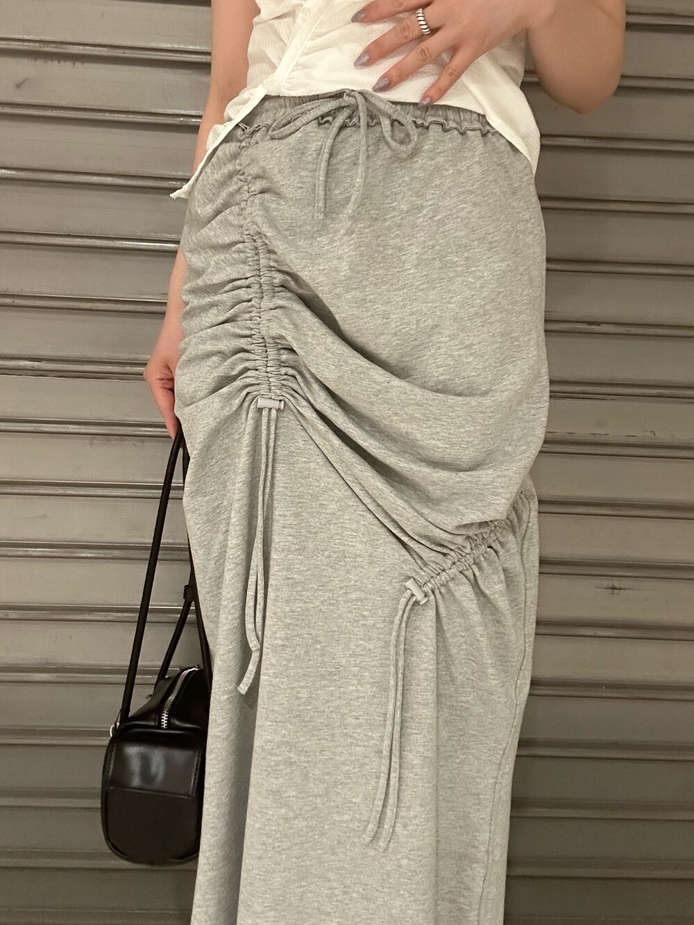 ホワイト系のTシャツ/カットソー、グレー系のスカート、ブラック系のサンダルを着用したレディースの夏コーディネートの6枚目の写真