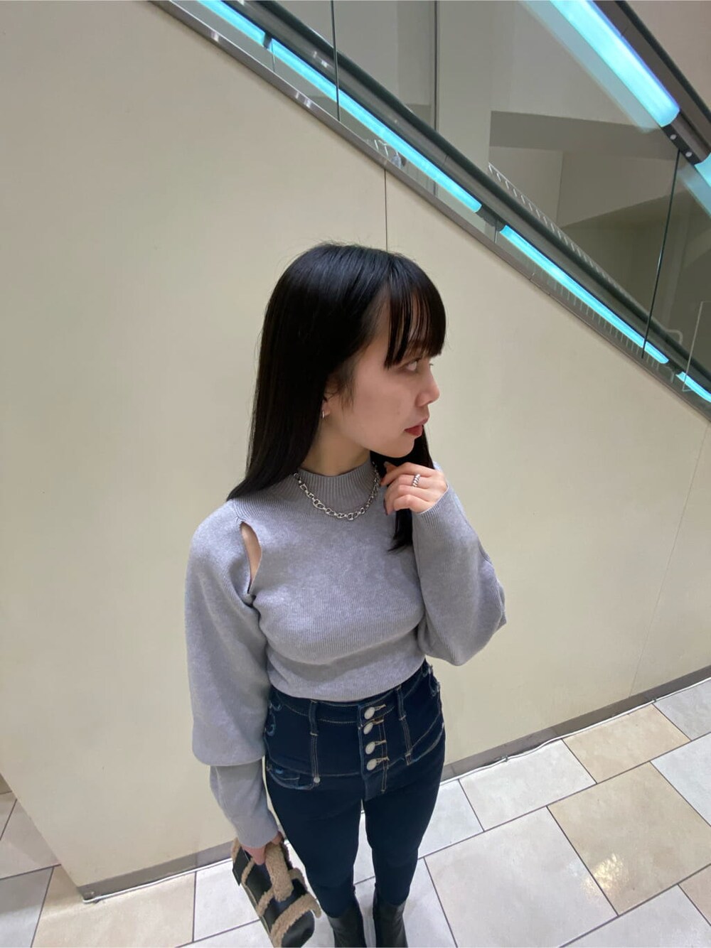 ブラック系のハンドバッグ、ブルー系のデニムパンツ、グレー系のニット/セーターを着用したレディースの秋コーディネートの2枚目の写真