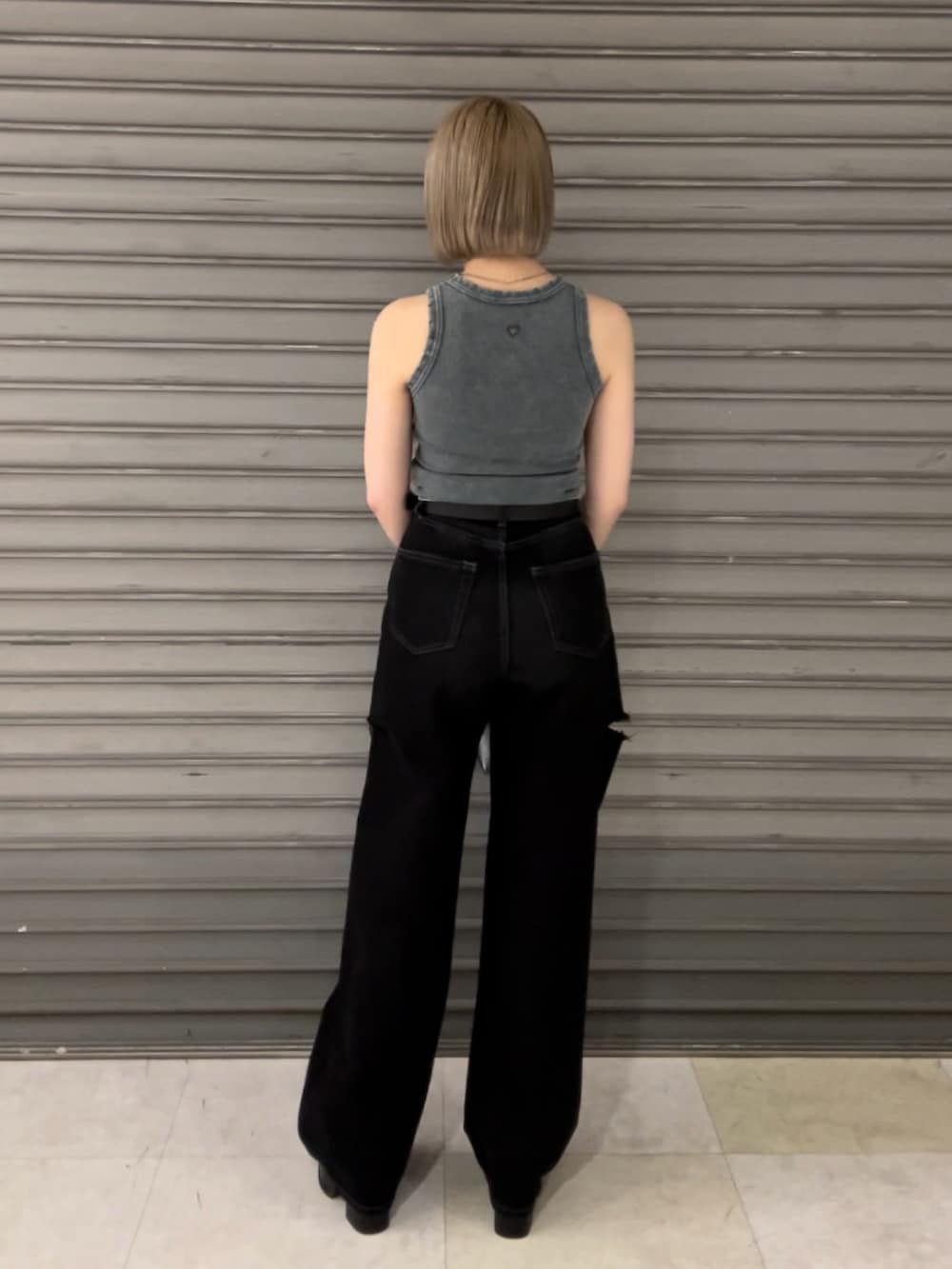 ブルー系のタンクトップ、ブラック系のデニムパンツ、ブラック系のハンドバッグを着用したレディースの夏コーディネートの3枚目の写真