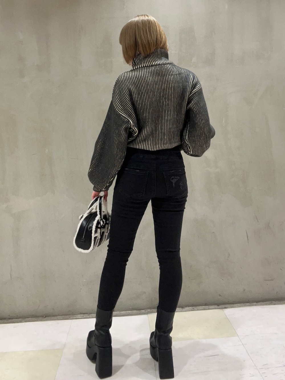 ブラック系のニット/セーター、ブラック系のブーツ、ブラック系のデニムパンツを着用したレディースの秋コーディネートの3枚目の写真