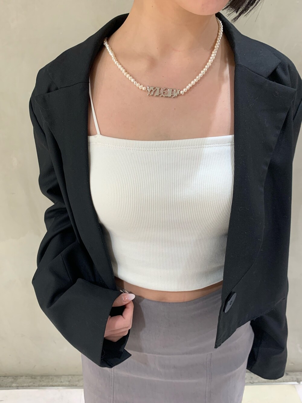 ホワイト系のキャミソール、ブラック系のブーツ、ブラック系のテーラードジャケットを着用したレディースの冬コーディネートの3枚目の写真