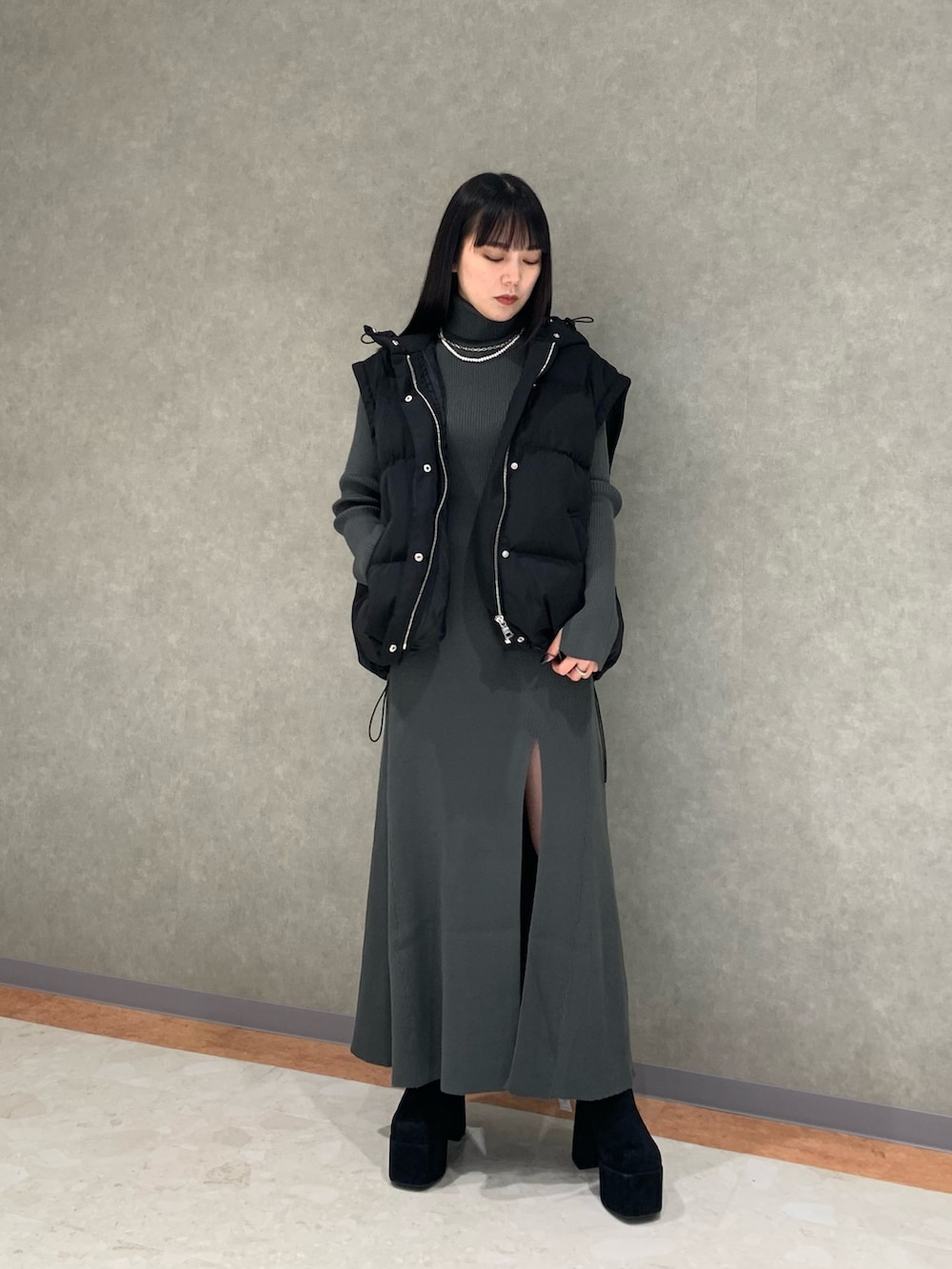 グレー系のワンピース、ブラック系のダウンジャケット/コート、ブラック系のブーツを着用したレディースの冬コーディネートの4枚目の写真