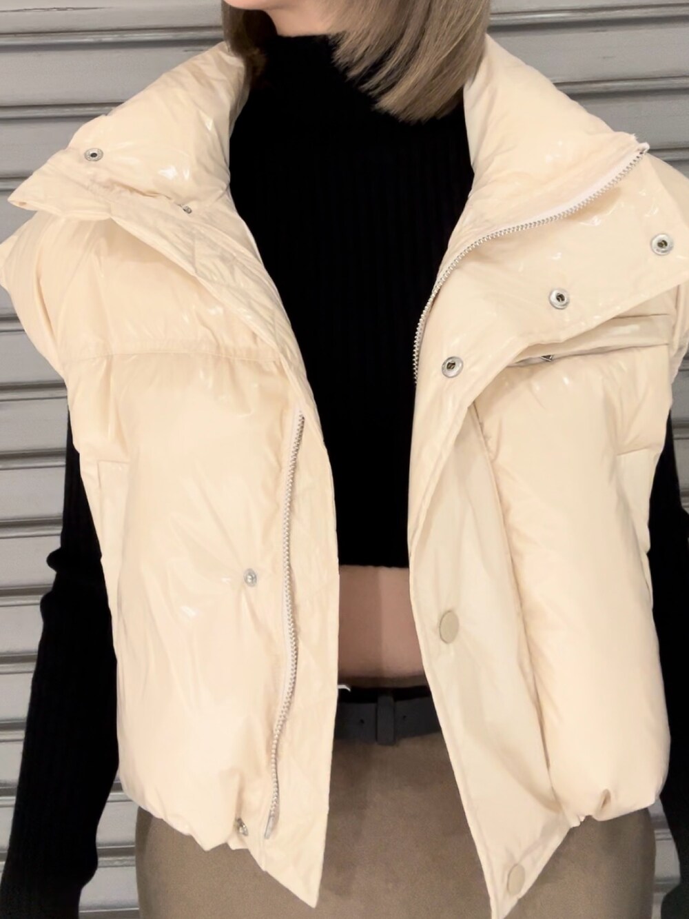 ホワイト系のダウンベスト、ブラック系のニット/セーター、ベージュ系のスカートを着用したレディースの秋コーディネートの7枚目の写真