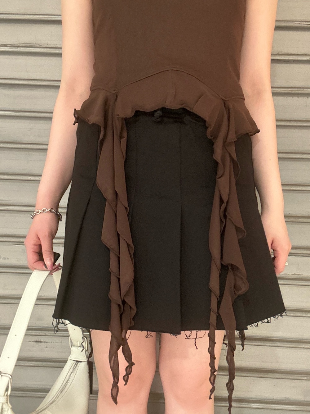 ブラウン系のTシャツ/カットソー、ブラック系のスカート、ブラック系のサンダルを着用したレディースの春コーディネートの5枚目の写真