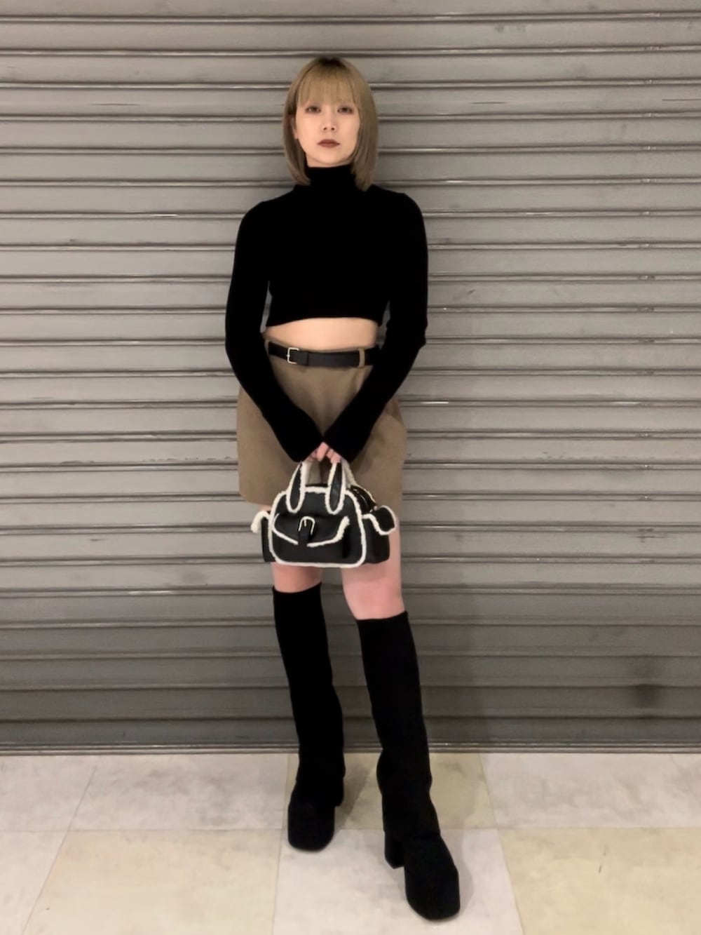 ホワイト系のダウンベスト、ブラック系のニット/セーター、ベージュ系のスカートを着用したレディースの秋コーディネートの2枚目の写真