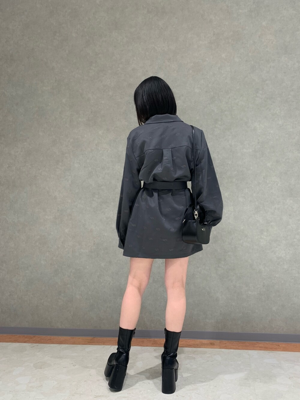 グレー系のワンピース、ブラック系のハンドバッグ、ブラック系のブーツを着用したレディースの冬コーディネートの2枚目の写真