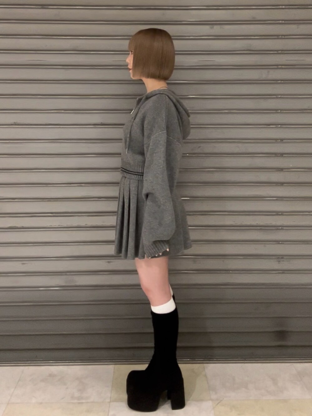 グレー系のニット/セーター、グレー系のスカート、その他のブーツを着用したレディースの秋コーディネートの3枚目の写真