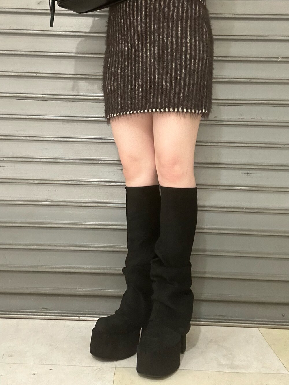 ブラウン系のニット/セーター、ブラウン系のスカート、ブラック系のブーツを着用したレディースの秋コーディネートの6枚目の写真