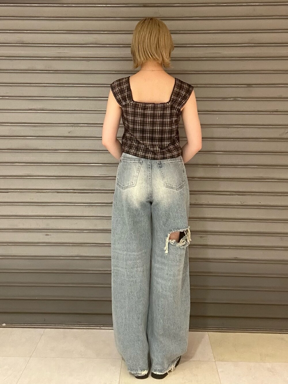 ブラウン系のタンクトップ、ブルー系のデニムパンツ、ブラック系のサンダルを着用したレディースの夏コーディネートの3枚目の写真