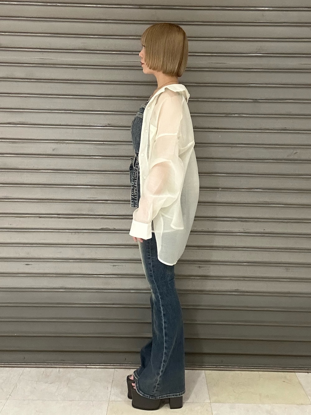 ブルー系のサロペット/オーバーオール、ホワイト系のシャツ/ブラウス、ブラック系のサンダルを着用したレディースの春コーディネートの2枚目の写真