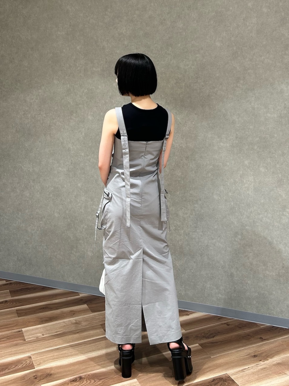 グレー系のワンピース、ブラック系のタンクトップ、ホワイト系のハンドバッグを着用したレディースの夏コーディネートの3枚目の写真