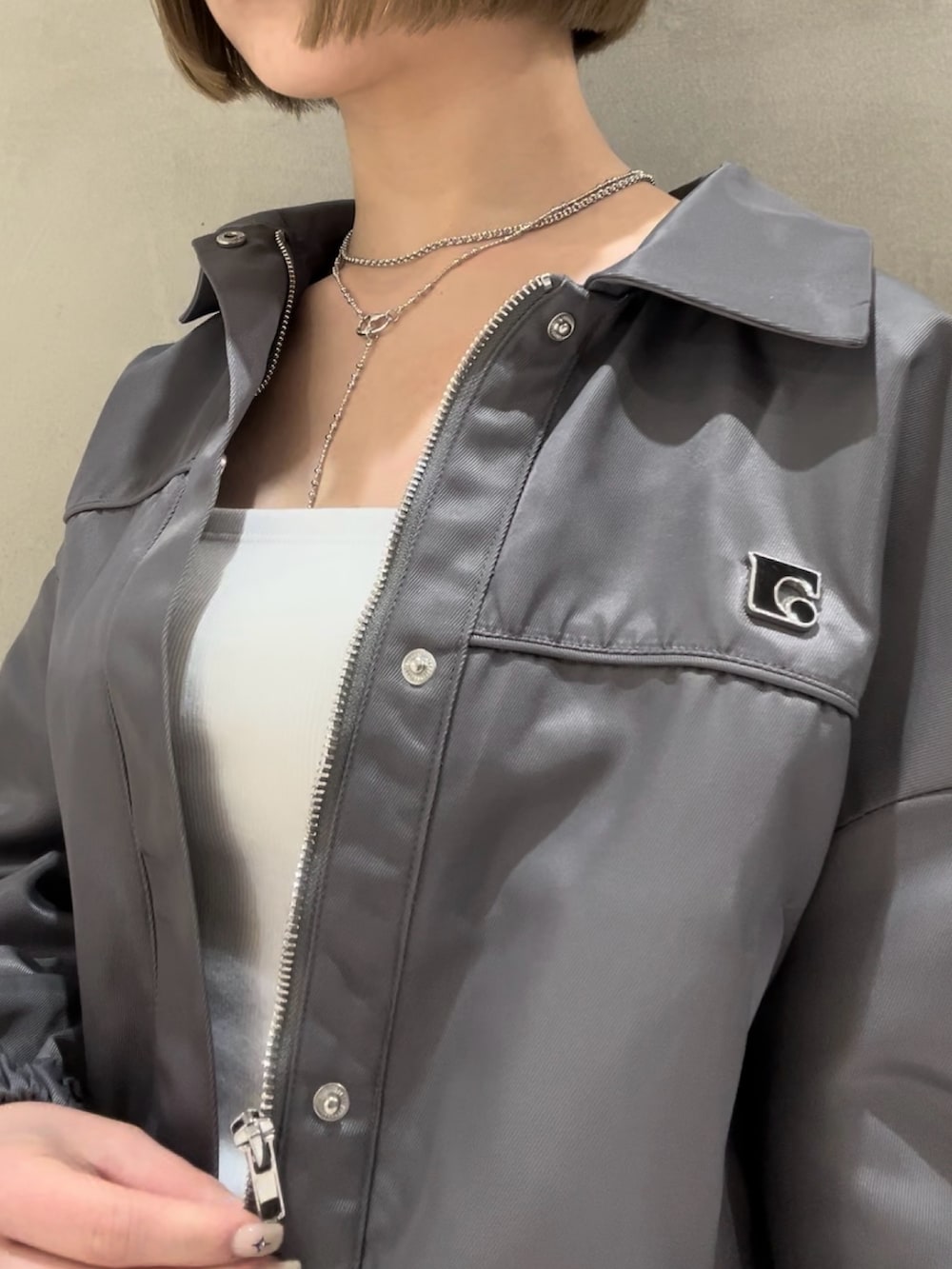 ホワイト系のキャミソール、ブラック系のショルダーバッグ、グレー系のブルゾンを着用したレディースの冬コーディネートの4枚目の写真