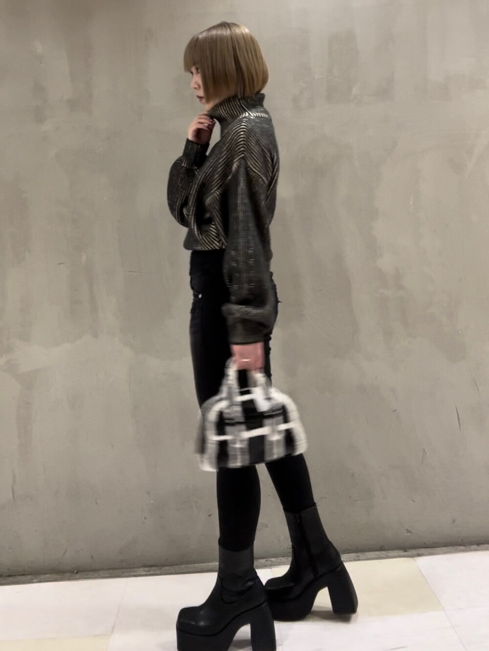 ブラック系のニット/セーター、ブラック系のブーツ、ブラック系のデニムパンツを着用したレディースの秋コーディネートの2枚目の写真