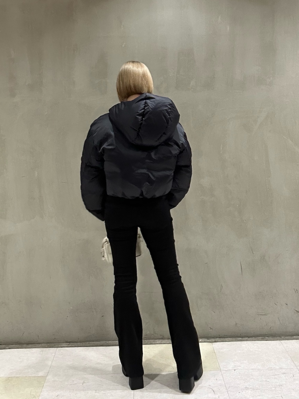 ホワイト系のダウンジャケット/コート、ブラック系のニット/セーター、ブラック系のデニムパンツを着用したレディースの冬コーディネートの6枚目の写真