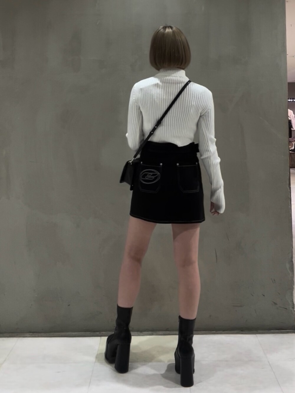 ホワイト系のニット/セーター、ブラウン系のブルゾン、ブラック系のスカートを着用したレディースの冬コーディネートの6枚目の写真