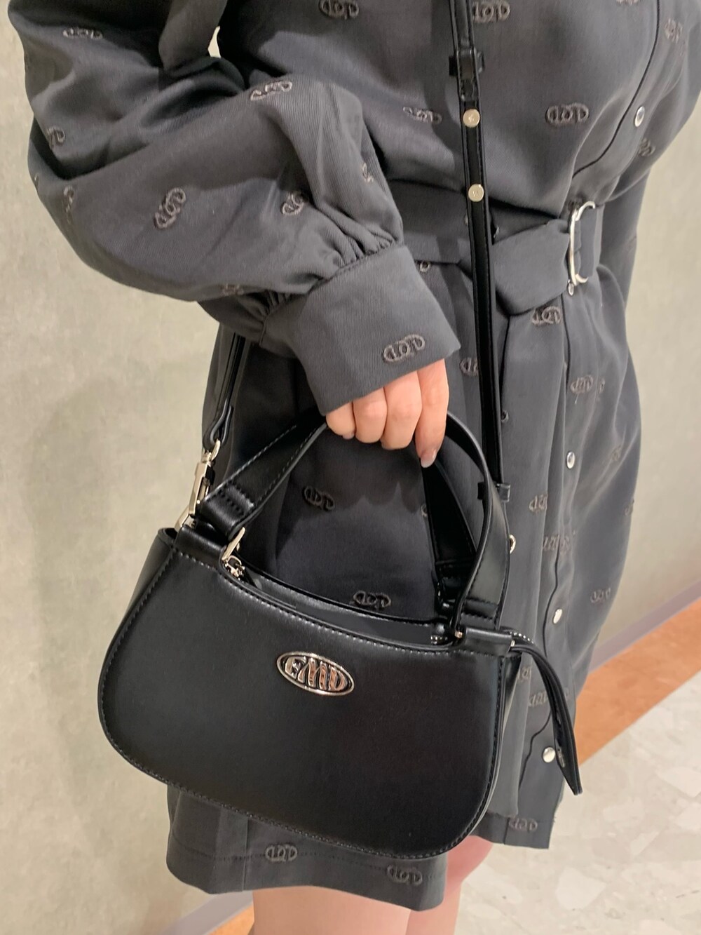 グレー系のワンピース、ブラック系のハンドバッグ、ブラック系のブーツを着用したレディースの冬コーディネートの4枚目の写真