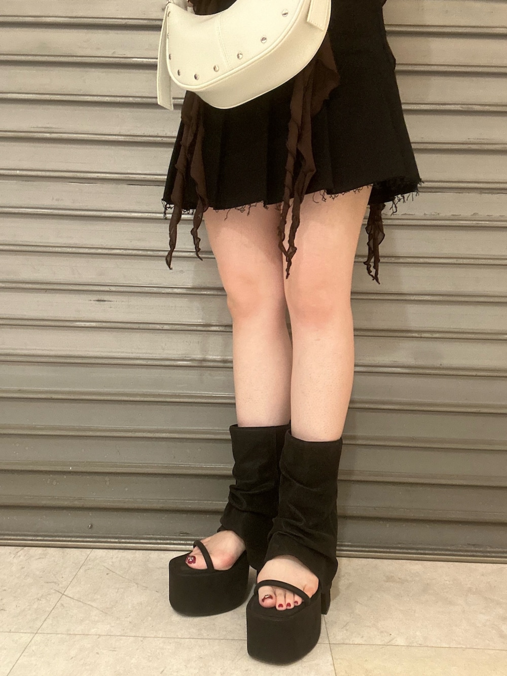 ブラウン系のTシャツ/カットソー、ブラック系のスカート、ブラック系のサンダルを着用したレディースの春コーディネートの6枚目の写真