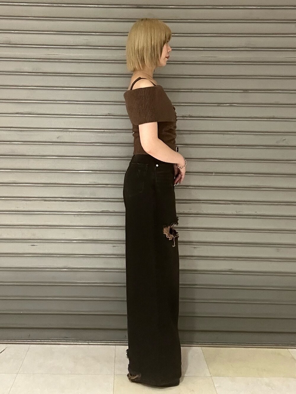 ブラウン系のニット/セーター、ブラック系のデニムパンツ、ブラック系のサンダルを着用したレディースの夏コーディネートの2枚目の写真